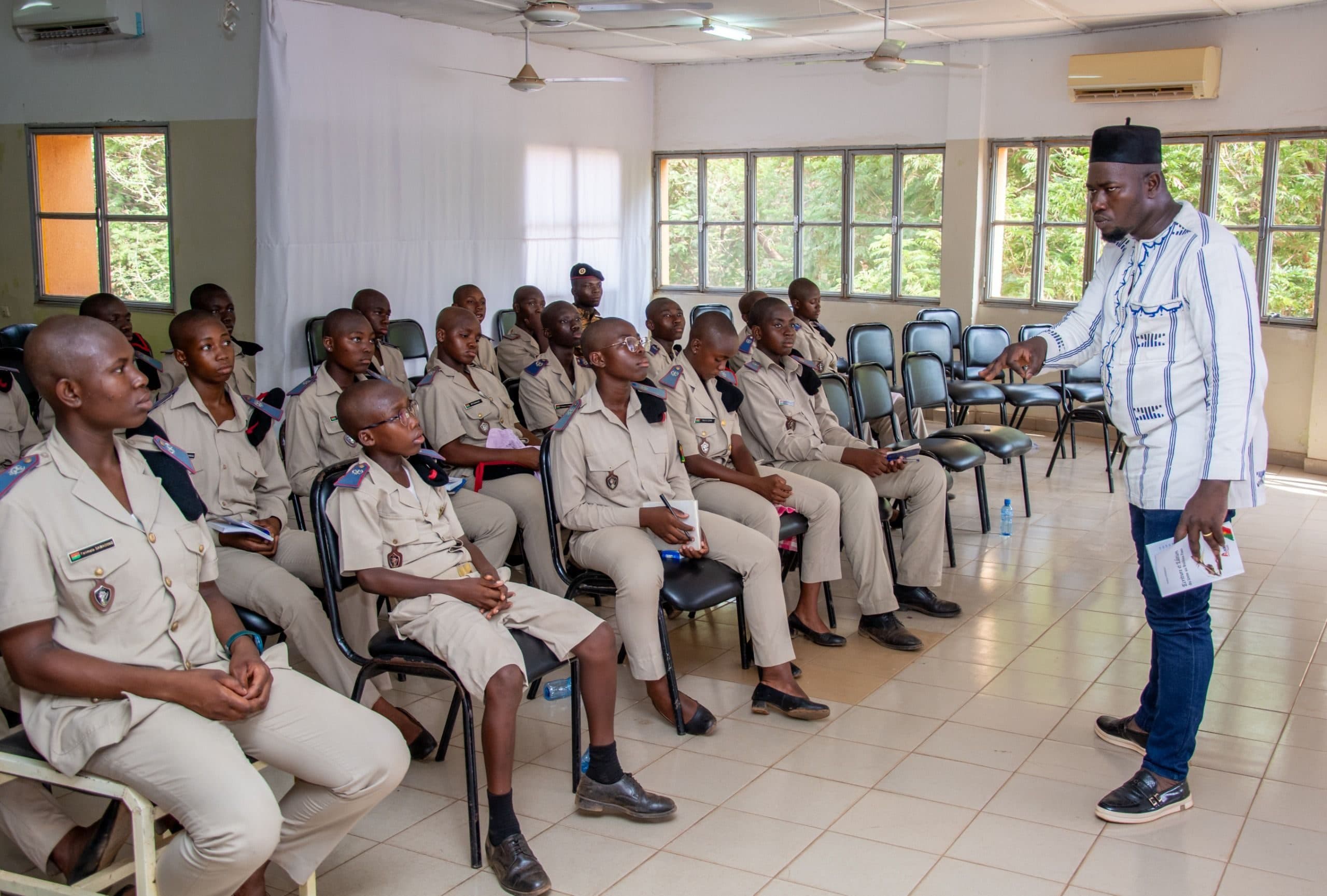 An instructor standing before a classroom of seated learners in uniform, speaking to the room.